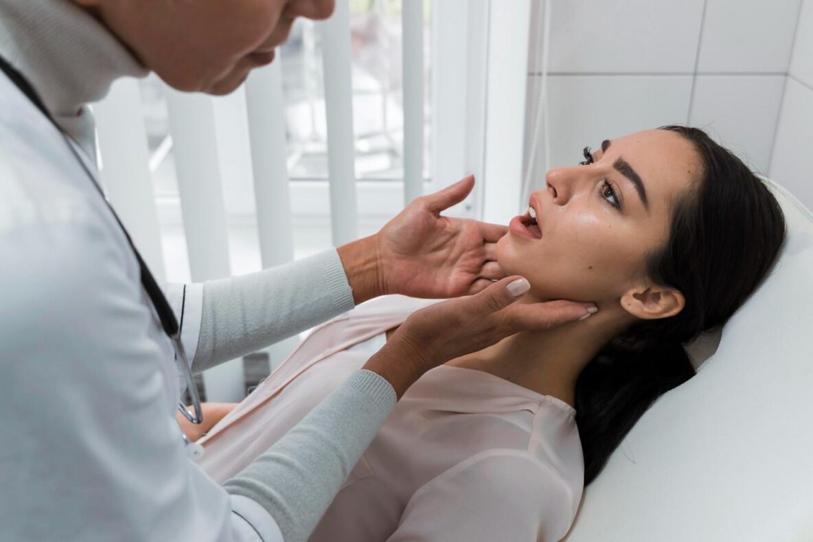 Dentist examining a woman’s jaw and mouth during a dental checkup while she reclines in a dental chair.